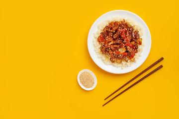 Sweet and sour pork on rice with red peppers, top view, copy space