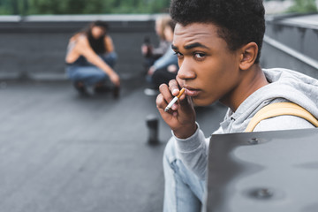 Wall Mural - selective focus of african american boy smoking cigarette and looking away