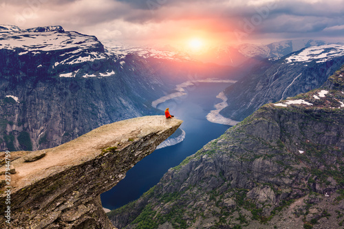 Fotografía  Norway, A woman sits on the mountain's cliff edge of Trolltunga