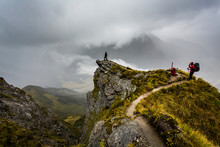 Figures Overlooking A Mountain Valley Hidden By Clouds In New Zealand