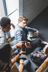 Wall Mural - high angle view of smiling teenagers sitting on stairs and clinking