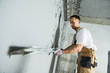 © Kadmy - Plasterer using screeder spraying putty plaster mortar on wall