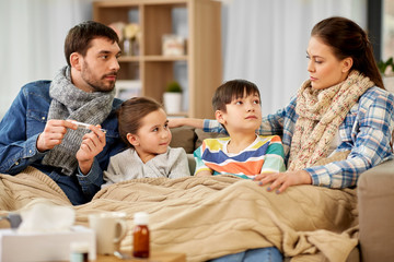 Wall Mural - family, health and people concept - father with thermometer, mother and ill children having fever at home