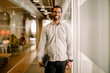 © Maskot - Portrait of smiling businessman standing in office corridor