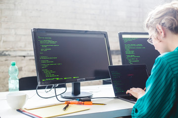 Side view of businesswoman working on start-up project while coding in office