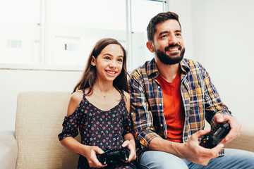 Wall Mural - Smiling father and daughter playing video game at home