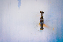 Old Rusty Water Tap Without Water At An Outdoor Stucco Wall. Water Shortage Concept. Copy Space For Your Text