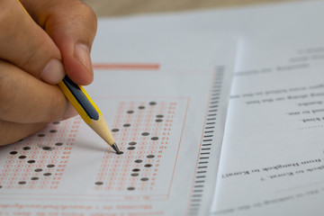 Wall Mural - school or university students hands taking exams, writing examination room with holding pencil on op
