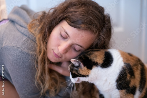 Closeup Portrait Of Young Woman Bonding With Calico Cat Pet