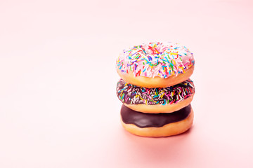 Three tasty doughnuts on pink background.