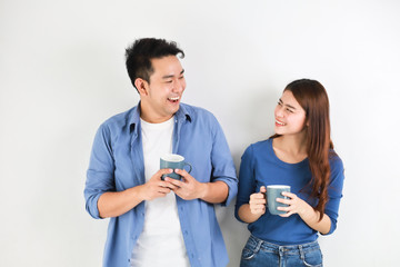 Wall Mural - Asian couple in blue shirt on white background with cup of coffee happy and smile mood