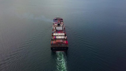 Wall Mural - Aerial view, Cargo vessel sail to the sea with peaceful wave. Professional business logistics and transportation of cargo ship. The tilt reveal shot.