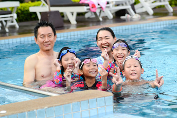 Happy Asian family enjoying in pool together, lifestyle concept.