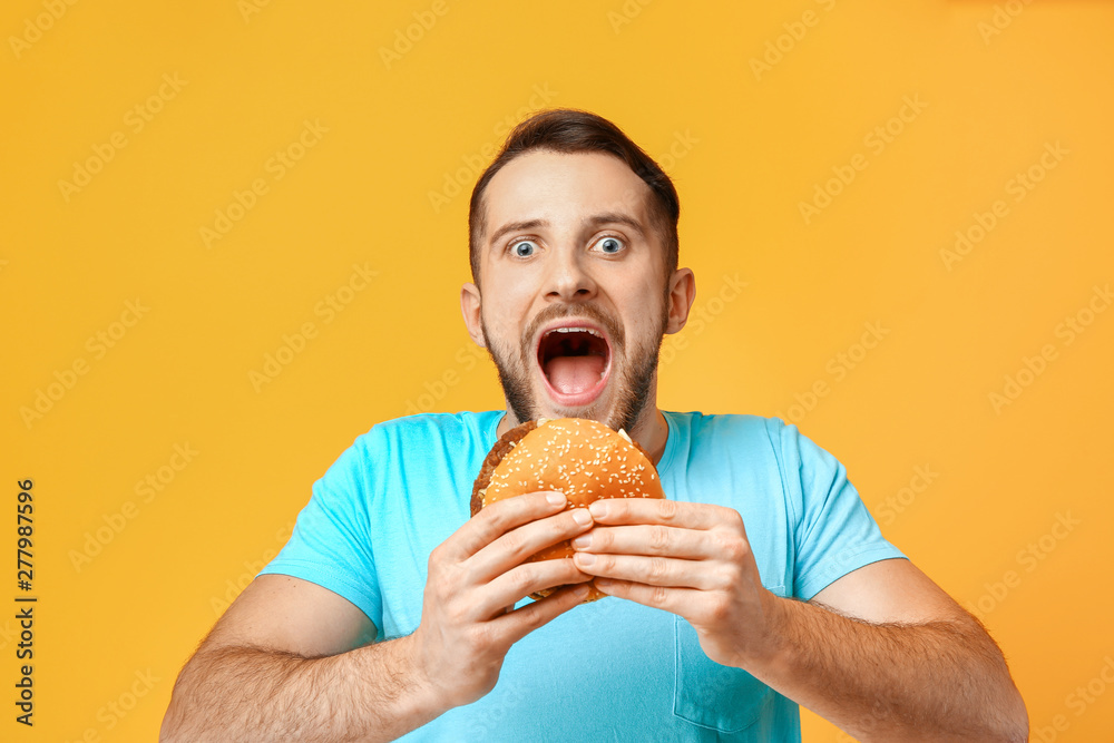 Man with burger on color background