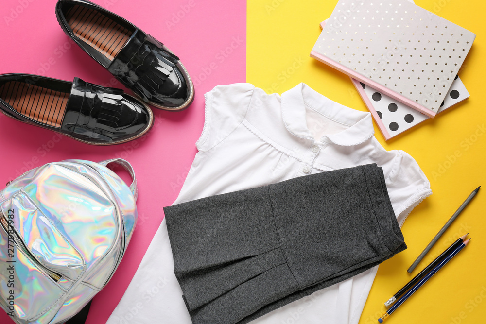 Stylish school uniform with backpack and stationery on color background