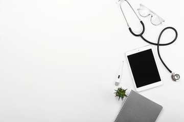 Stethoscope, tablet computer, notebook and thermometer on white background