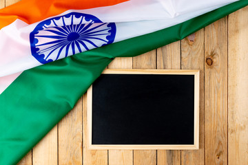 Top view of National Flag of India with chalkboard on wooden background.