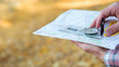 Traveler lifestyle. Closeup of man hands holding compass and map. Blur yellow grass background. Copy space.
