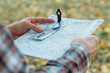 Autumn journey. Closeup of man hands holding compass and map. Blur yellow grass background.