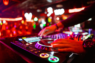 Dj mixing outdoor at beach party festival with crowd of people in background - Summer nightlife view of disco club outside - Soft focus on hand - Fun ,youth,entertainment and fest concept