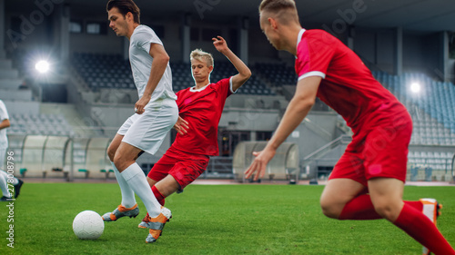 Professional Soccer Player Leads with a Ball, Masterfully Dribbling and Bypassing Sliding Tackles of His Opponents. Two Professional Football Teams Playing. Low Angle Shot.