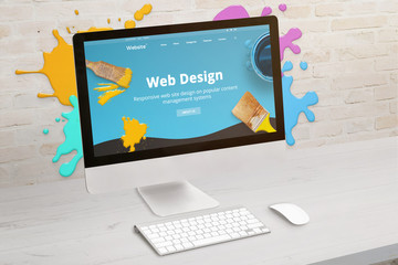 Wall Mural - Concept of web design studio with coimputer display and color drops on brick wall. Modern web design teme on screen. Concept of modern graphic studio desk.