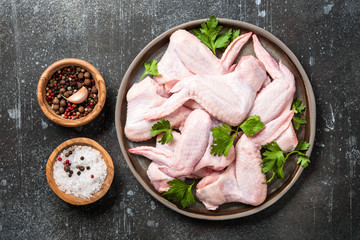 Fresh raw chicken wings on ceramic plate and spices for cooking