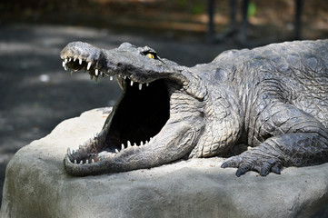 Poster - Plastic figurine of crocodile on stone.