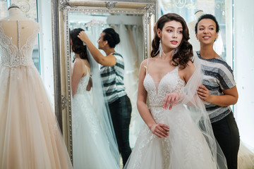 Wall Mural - Beautifu bride choosing wedding dress in a wedding salon