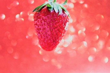 juicy red strawberry berry on a red shiny background, close-up, selective focus, blur