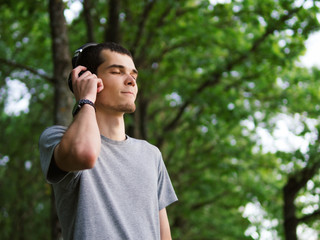 Wall Mural - Beautiful man in headphones listening to music outdoor.