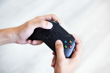 Black joystick in hands isolated on white background. The guy is playing on the console. Computer gaming technology play competition videogame control confrontation concept. Cyberspace symbol