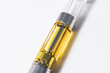 Cannabis oil liquid extract up-close in plastic cartridge, to vape and inhale the medicinal cannabinoids THC & CBD found in marijuana plants. Macro shot isolated on white background.