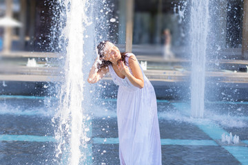 young woman escaping heat wave in city fountain