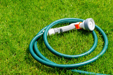 Green hose for watering lies on grass, lawn