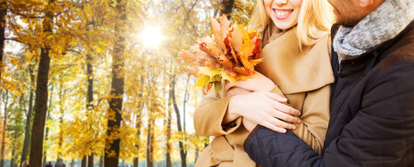 Wall Mural - love, relationship, family and people concept - close up of smiling couple with bunch of leaves hugging in autumn park