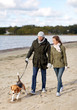 © Syda Productions - pet, domestic animal and people concept - happy couple with beagle dog on leash walking along autumn beach