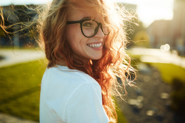 portraits of a charming red-haired girl with a cute face. girl posing for the camera in the city cen