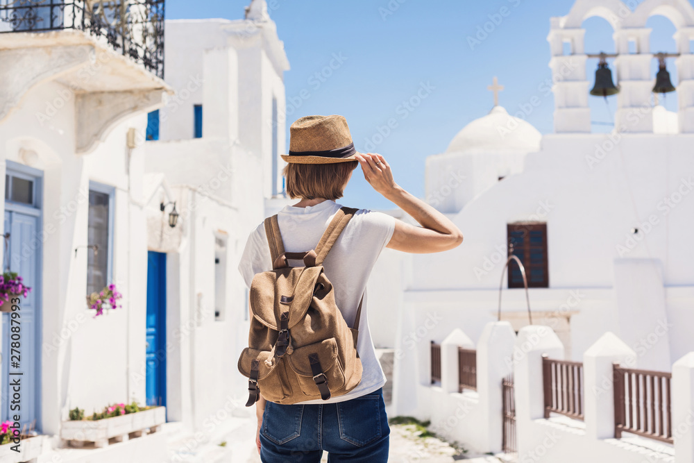 Traveler girl enjoying vacations in Greece. Young woman wearing hat looking at greek village. Summer holidays, vacations, travel, tourism concept. - obrazy, fototapety, plakaty 