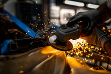 Worker Cutting, Grinding And Polishing Motorcycle Metal Part With Sparks Indoor Workshop, Close-up.