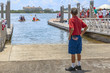© Manny DaCunha - A retired veteran looks down a boat launching slip as the small boats drift away  paddling. He stands alone on the 4th of July wearing red white and blue colors with American flag on his shorts