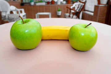 Two green apples and a banana in the center in the middle of the garden