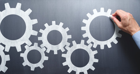 Poster - Business operation. Businessman drawing gears on chalkboard.