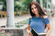 © Adamov - Whatever you decide to do, make sure it makes you happy. Young cheerful woman standing with a notebook outdoors. Copy space on the left side