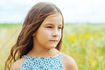 portrait of a little adorable girl with long hair in the field