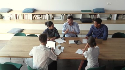 Wall Mural - Diverse employees group sit at table listen to male leader