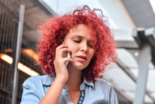 Worried Woman Receiving Unpleasant Call On Mobile Outdoors