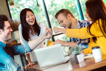 creative business meeting with caucasian and asian co worker discuss with paper laptop and happiness and joyful cafe background