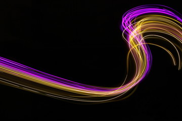 Wall Mural - Long exposure photograph of neon purple and gold colour in an abstract swirl parallel lines pattern against a black background. Light painting photography.