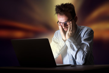 Young handsome businessman working late at night in the office with warm lights in the background